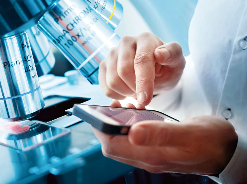 Microscope and physician looking at the microscope view directly on his smartphone